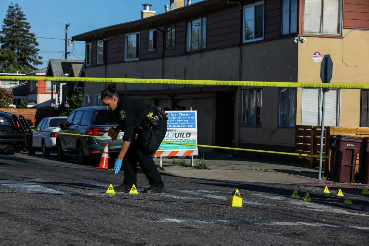 Oakland police Officer A. Goodard works a crime scene at School St. and Pleitner Ave. following a shooting on Friday, June 25, 2021, in Oakland, Calif. Oakland is shifting some money from the police budget over to violence prevention and other services.