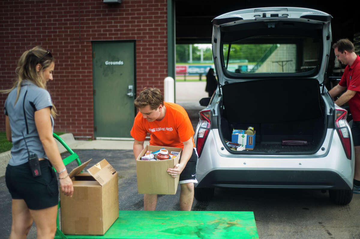 Volunteers work to organize donated food items, which were collected through the United Way's Summer Stock Up food drive, Tuesday, June 29, 2021 at Dow Diamond. The donated items will be distributed by Hidden Harvest to food pantries throughout the region. (Katy Kildee/kkildee@mdn.net)