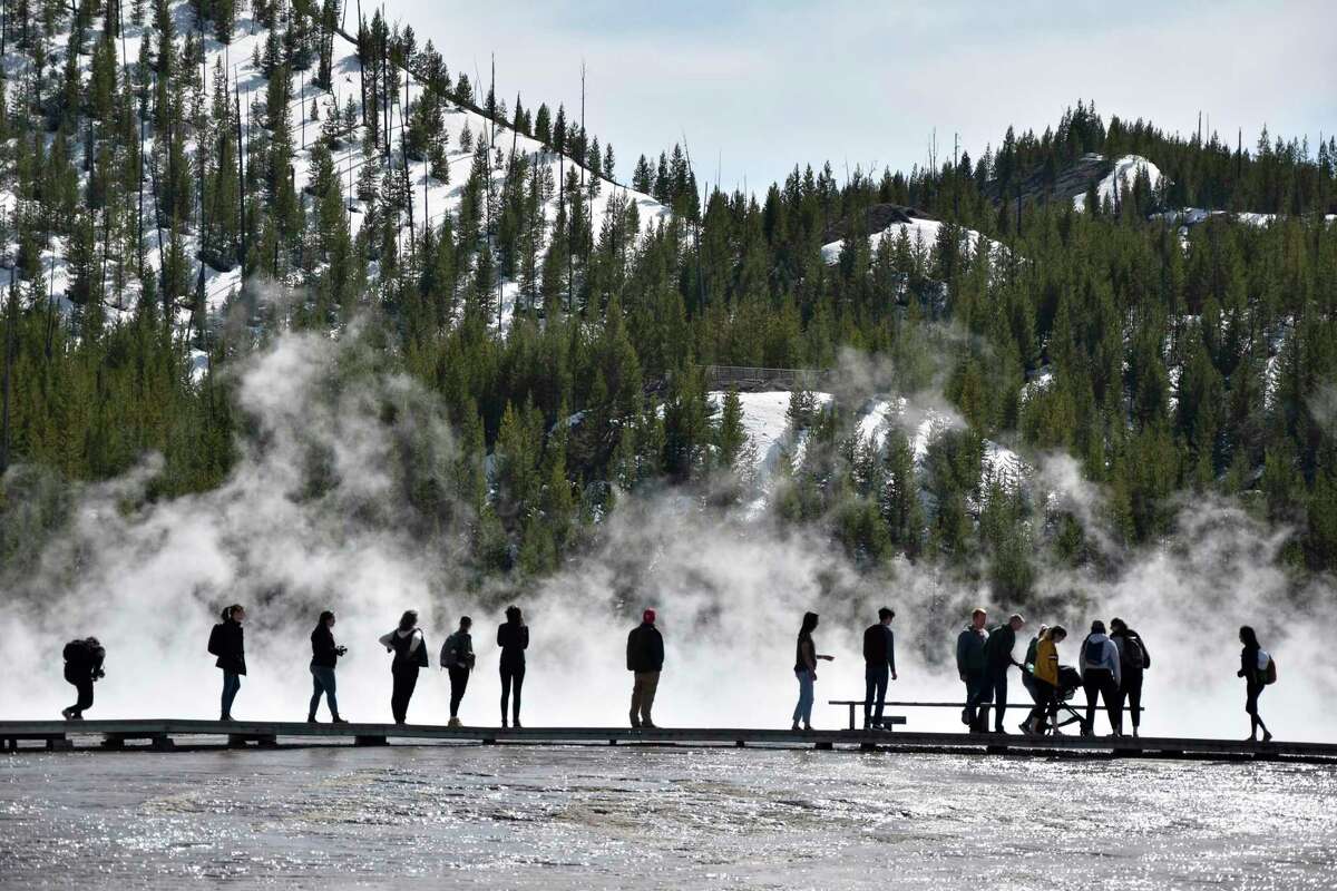Visitors are seen at Grand Prismatic Spring in Yellowstone National Park, Wyoming on May 1, 2021. A study by federal and university researchers says average park temperatures in recent decades were likely the warmest of the last 800,000 years. (AP Photo/Iris Samuels)