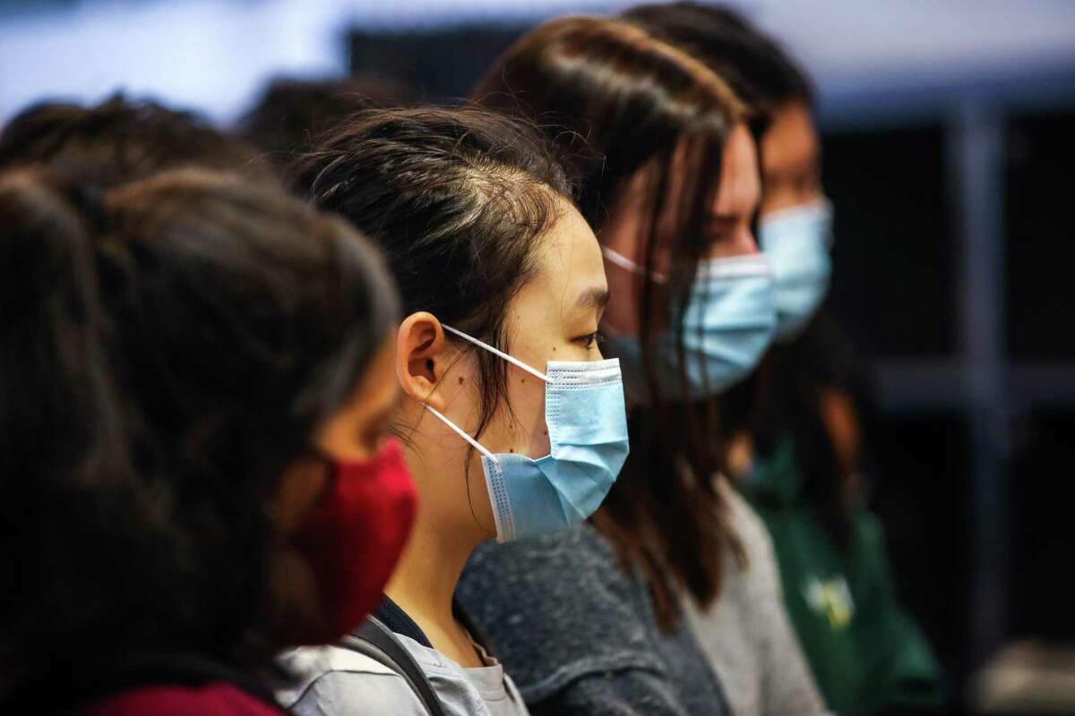 Masked graduates from San Jose’s Harker School listen to poet Neeli Cherkovski as he speaks to them during their tour of the Beat Museum on Saturday in San Francisco. Los Angeles County recommended Monday that even vaccinated people resume wearing masks in indoor public settings because of the spreading delta variant of the coronavirus.