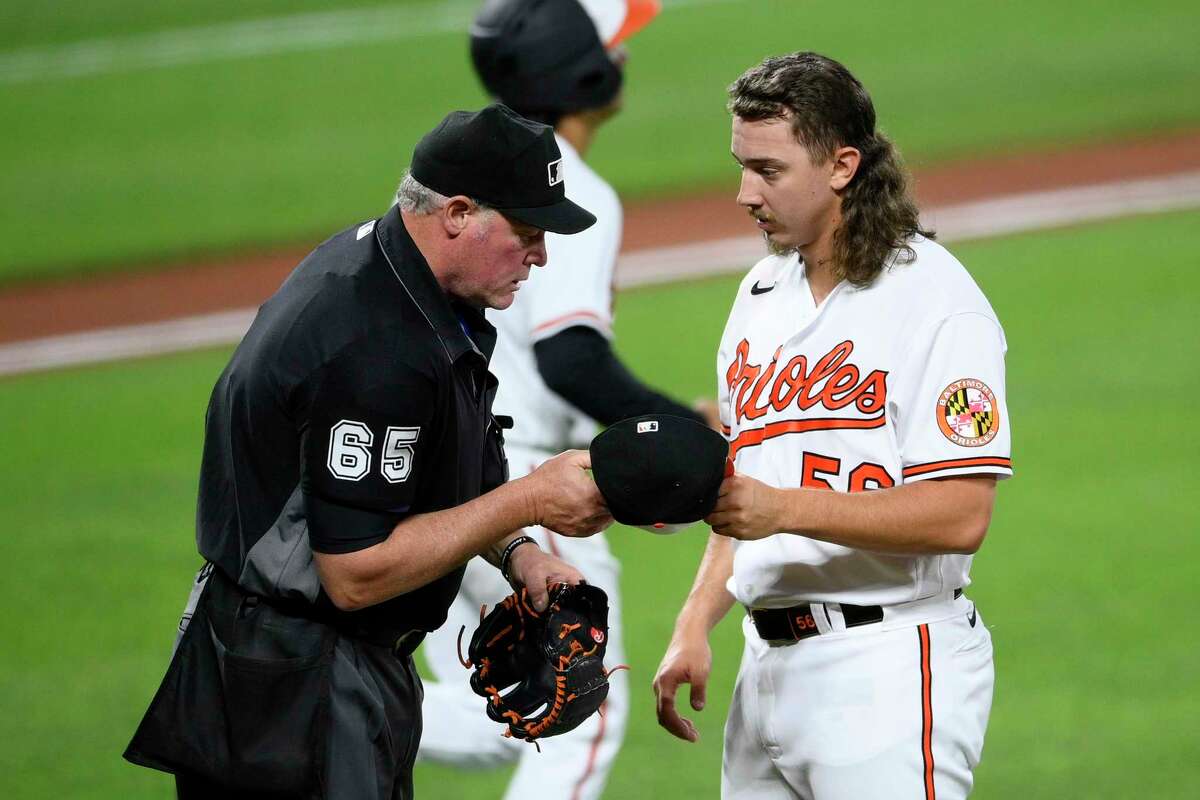 Baltimore Orioles relief pitcher Hunter Harvey, right, has his hat and glove inspected by home plate umpire Ted Barrett, left, during the seventh inning of a baseball game against the Houston Astros, Tuesday, June 22, 2021, in Baltimore. (AP Photo/Nick Wass)