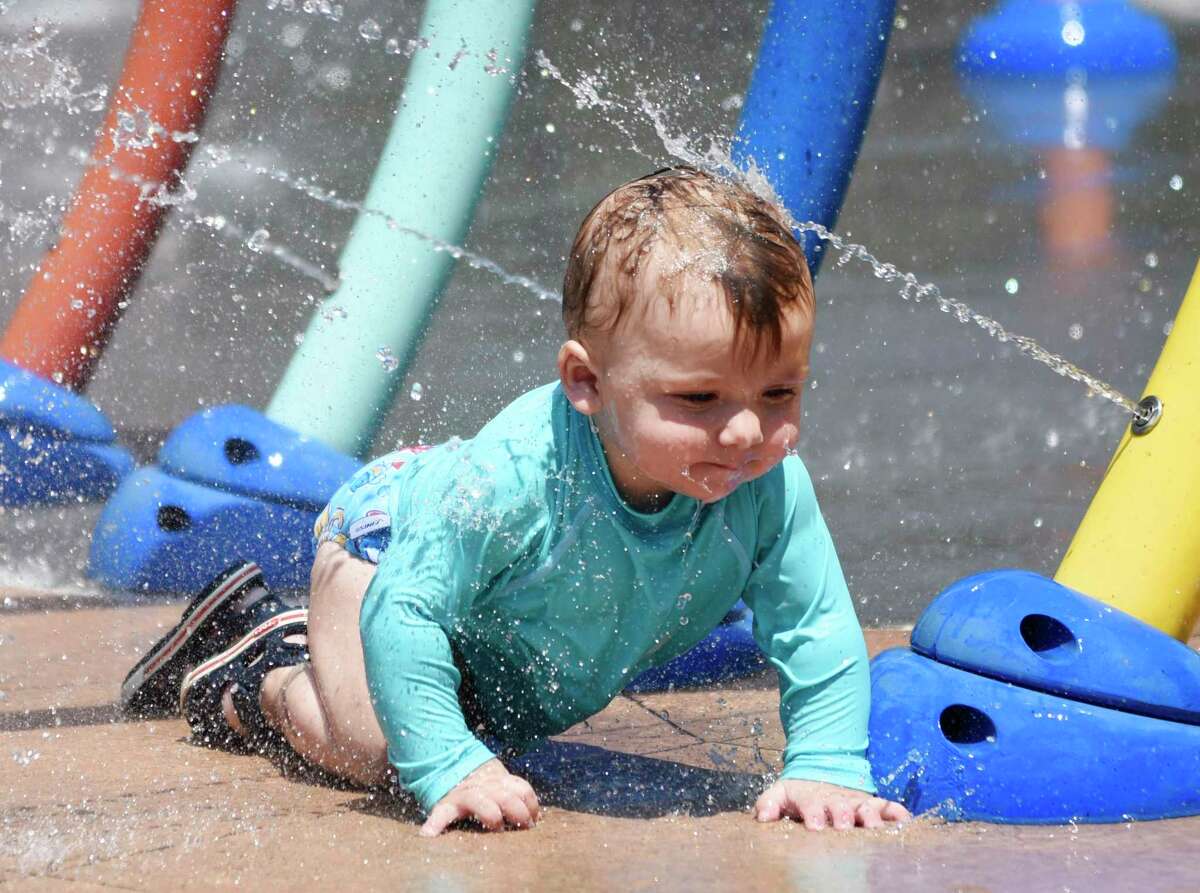 A baby crawls through across the splash pad at the Greenwich Pool in Byram Park in Greenwich, Conn. Tuesday, June 29, 2021. Folks flocked to the pool as temperatures soared into the 90s Tuesday with more hot weather in the mid-90s expected Wednesday.