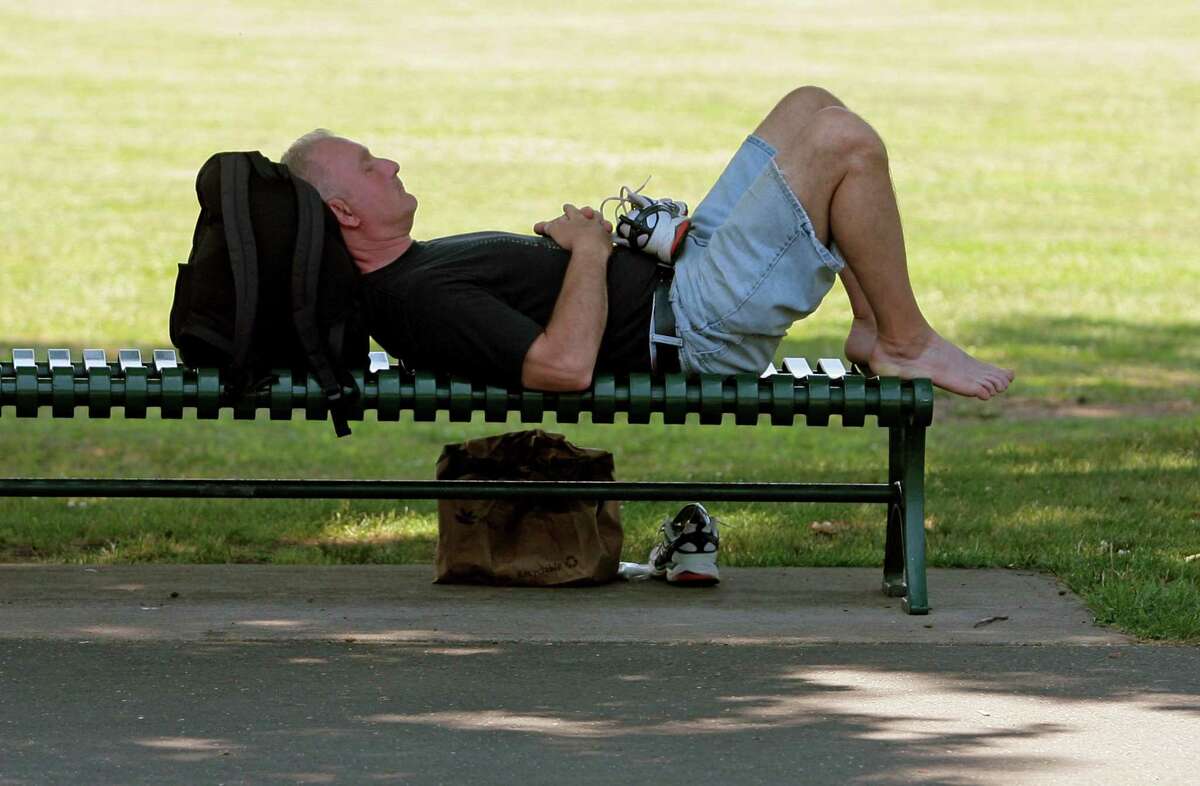 Paul, of Stamford, beats the heat by resting on a bench in the shade at Scalzi Park.in Stamford, Conn., on Friday June 18, 2021.