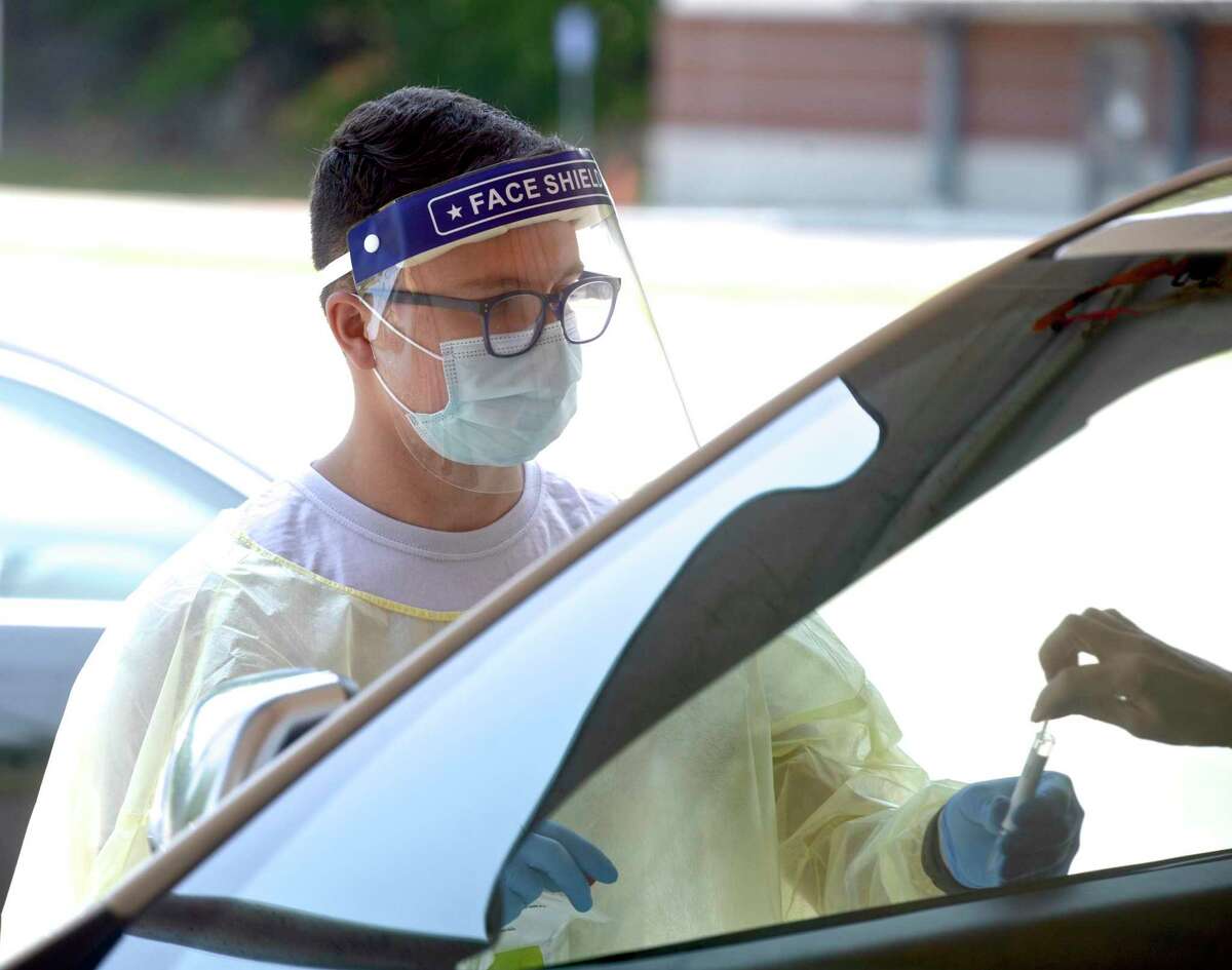 Peter Avila, a COVID testing associate, collects a self administered COVID-19 test from a patient at the Community Health Center COVID-19 testing site on the Western Connecticut State University Westside Campus. Tuesday, June 29, 2021, in Danbury, Conn.