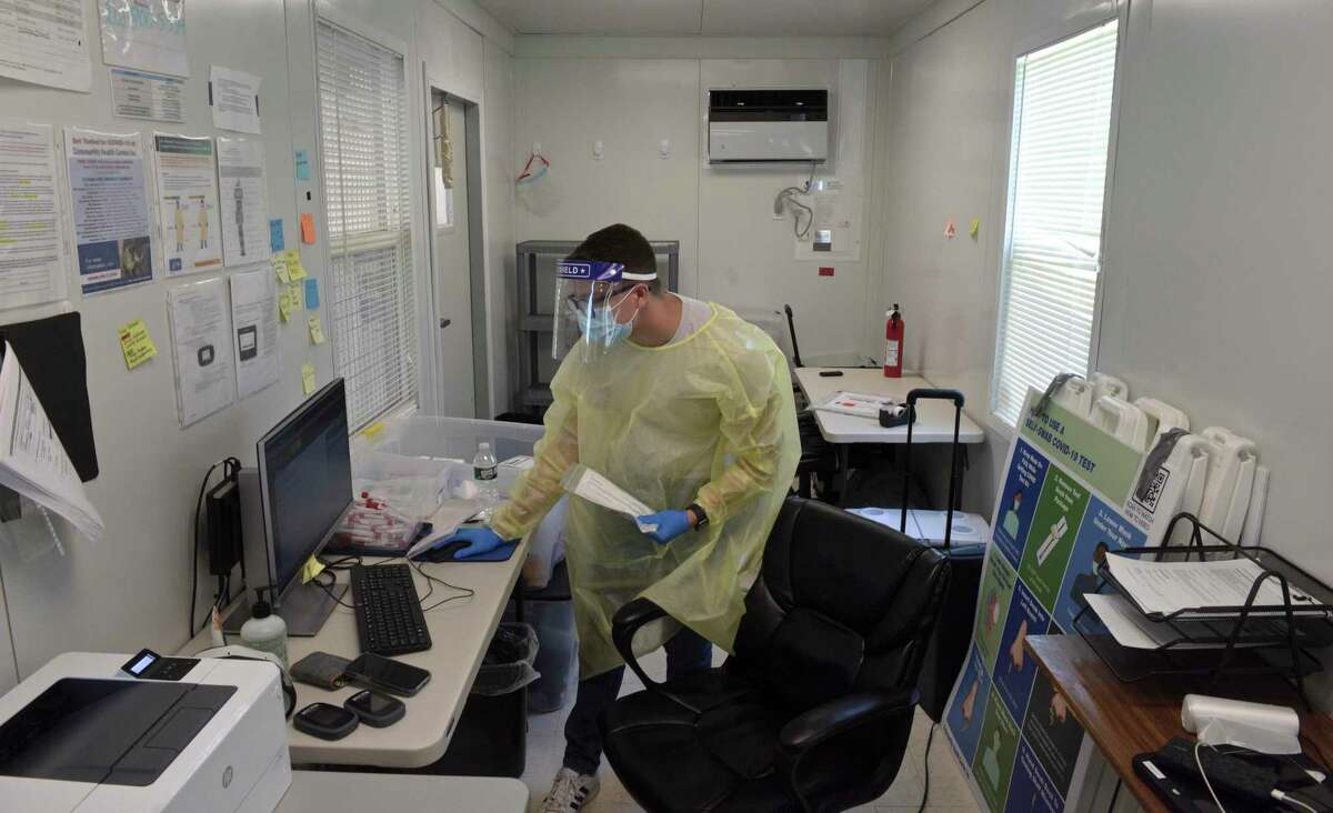 Peter Avila, a COVID testing associate, distributed and collected COVID-19 tests from a patients at the Community Health Center COVID-19 testing site on the Western Connecticut State University Westside Campus. Tuesday, June 29, 2021, in Danbury, Conn.