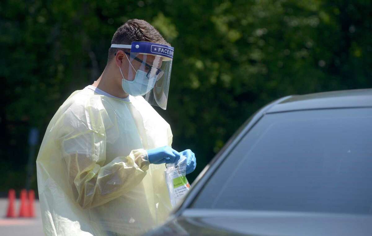 Peter Avila, a COVID testing associate, collects a self administered COVID-19 test from a patient at the Community Health Center COVID-19 testing site on the Western Connecticut State University Westside Campus. Tuesday, June 29, 2021, in Danbury, Conn.
