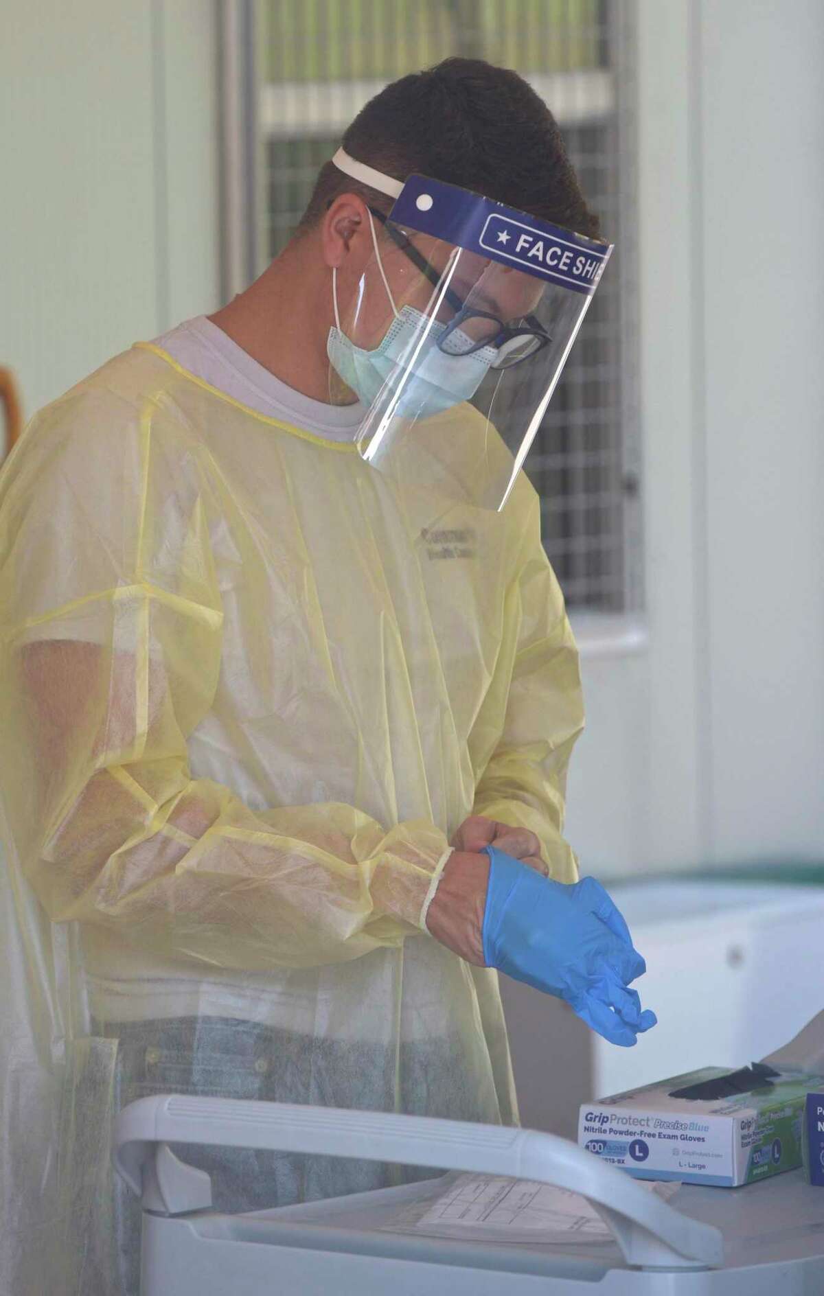 Peter Avila, a COVID testing associate, puts on glove to distribute a self administered test to a patient at the Community Health Center COVID-19 testing site on the Western Connecticut State University Westside Campus. Tuesday, June 29, 2021, in Danbury, Conn.