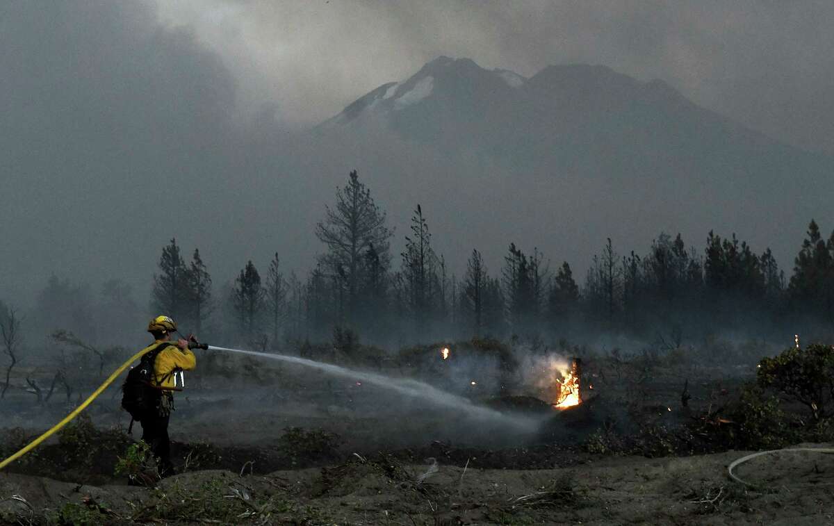 With Mount Shasta in the background, a firefighter cools down hot spots of the Lava Fire on Monday north of Weed.