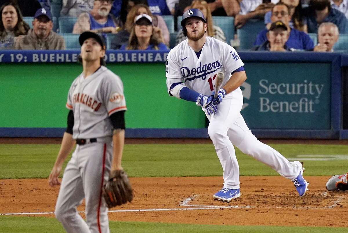 Los Angeles Dodgers' Max Muncy, right, runs to first as he hits a solo home run while San Francisco Giants starting pitcher Kevin Gausman watches during the third inning of a baseball game Tuesday, June 29, 2021, in Los Angeles. (AP Photo/Mark J. Terrill)