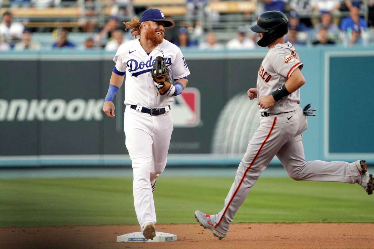 Los Angeles Dodgers third baseman Justin Turner, left, smiles at San Francisco Giants' Buster Posey as he forces him out at second to end the top of the first inning of a baseball game Tuesday, June 29, 2021, in Los Angeles. (AP Photo/Mark J. Terrill)