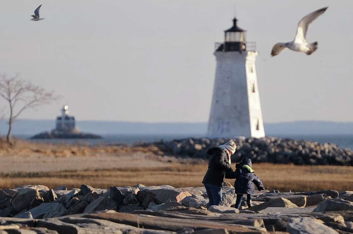 A woman and child make their way across the jetty towards the Fayerweather Island Lighthouse at Seaside Park in Bridgeport, Conn. on Monday, March 19, 2018. In the distance at left is Fairfield's Penfield Reef Light, marking the outer end of the Penfield Reef, a hazard to navigation.