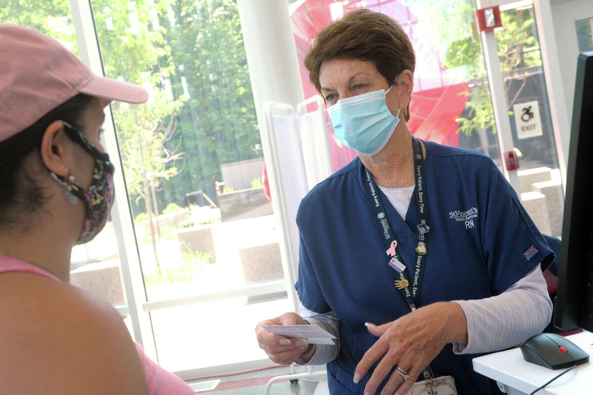 Wilza Cordero, of Ansonia, receives her vaccination card from St. Vincent's Medical Center nurse Mo Blees following her second COVID-19 vaccination shot at the mass vaccination clinic on Sacred Heart University's West Campus, in Fairfield, Conn. June 30, 2021. Wednesday was the final day of vaccination operations at the Fairfield location.