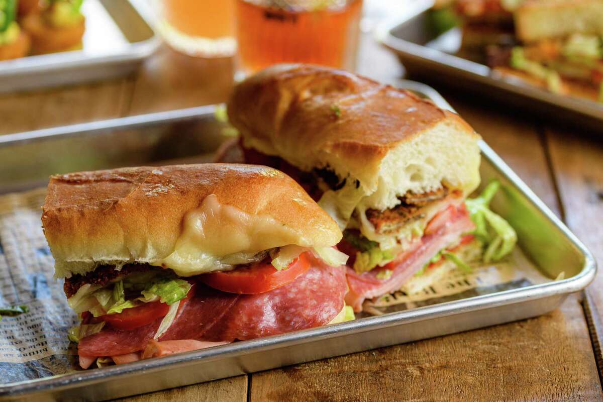 The Sanguiche is crispy eggplant, mortadella, salami, ham, provolone, roasted reds, lettuce, tomato, Italian dressing and fig jam, served hot on a 10-inch grinder roll.