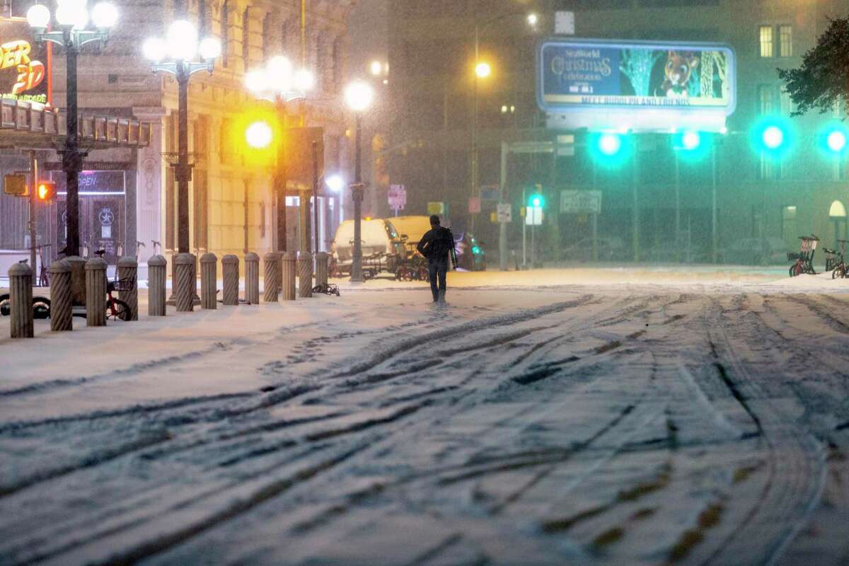 A lone person walks during the early morning hours of Feb. 15, 2021, on a blanket of snow on Alamo Street toward Houston Street. 