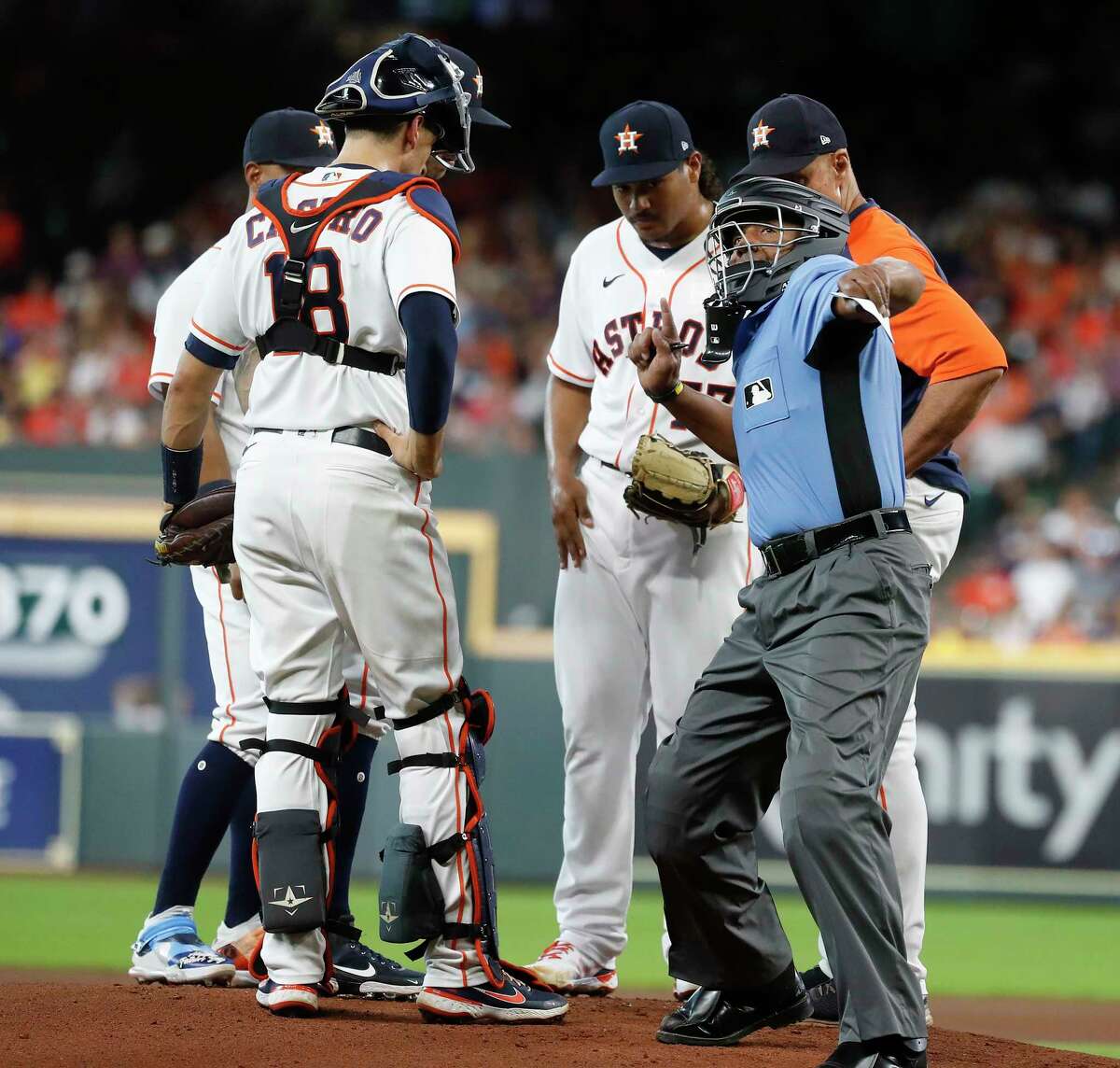 Home plate umpire CB Bucknor ejects Astros pitching coach Brent Strom (right) during a mound visit with starting pitcher Luis Garcia during the first inning Wednesday at Minute Maid Park.