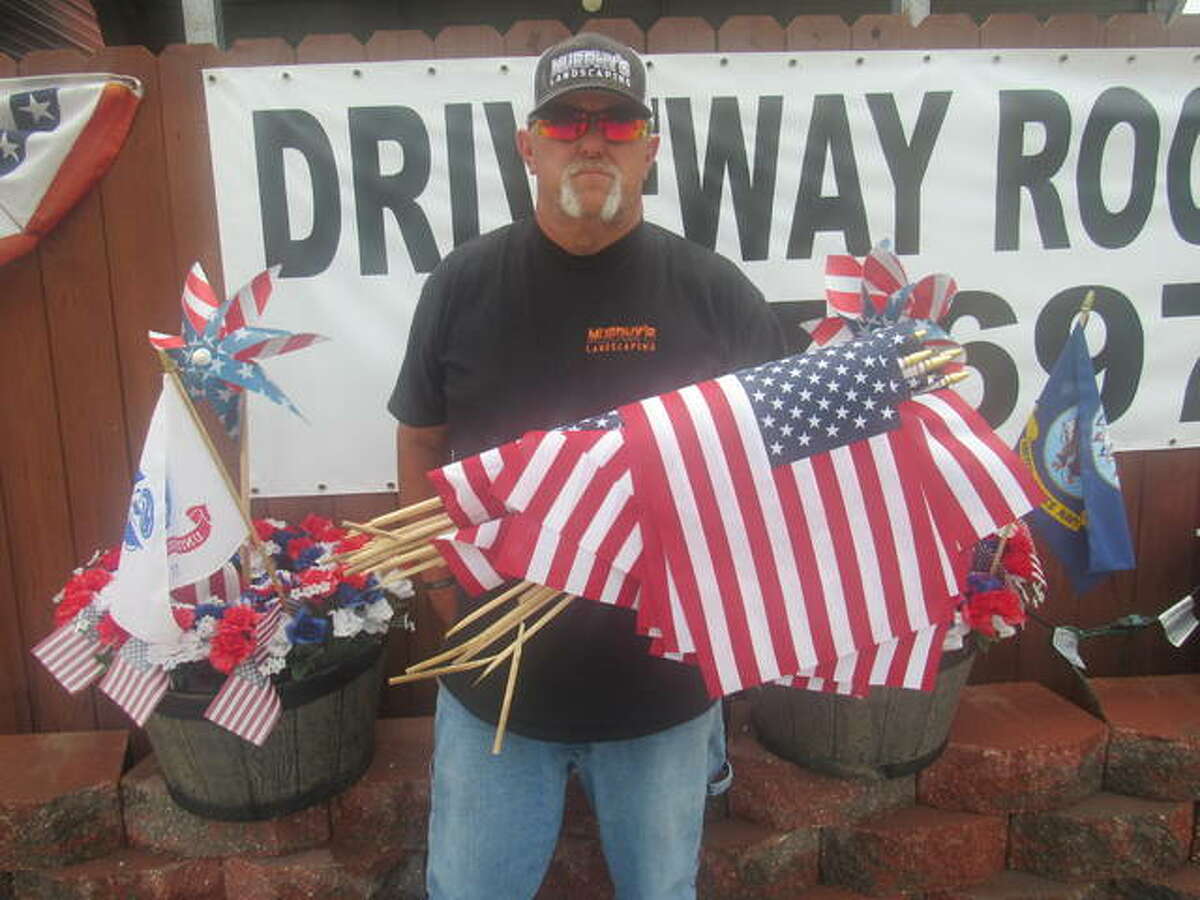 Jim Murphy holds some of flags knocked down Tuesday by an unknown motorist near his business in Cottage Hills. While some of the 250-300 flags were salvagable, Murphy said most were destroyed.