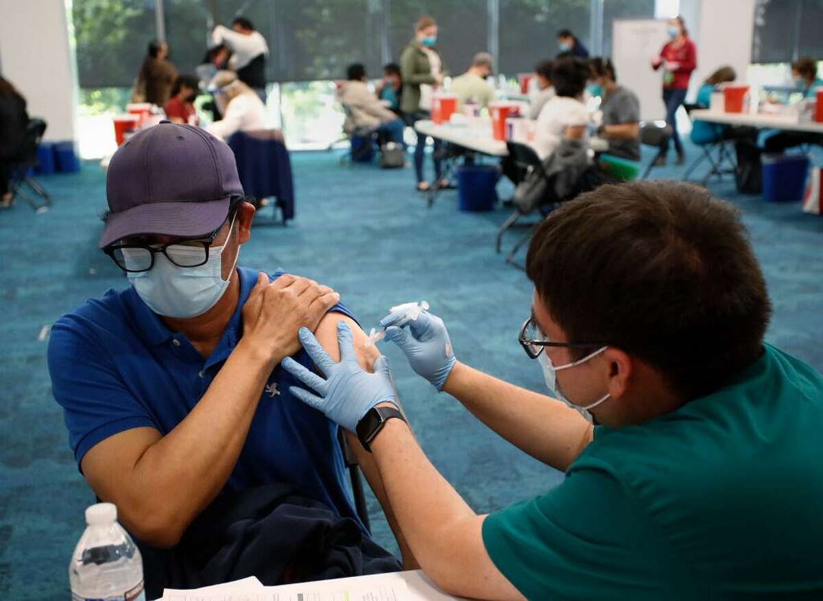 (left-right) Mariano Zelaya, of Redwood City, receives his vaccination from Carlos Martinez at the Facebook headquarters vaccine distribution center in Menlo Park, California on Saturday, April 10, 2021.