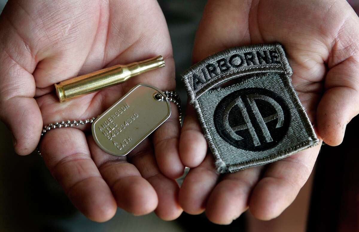 Military suicides have been persistent for years — and officials remain flumoxed about how to curb them. Here, a father holds an Airborne shoulder patch and a dog tag for his son who committed suicide. He also holds a spent cart a spent cartridge casing from the gun salute performed at this son's military funeral.