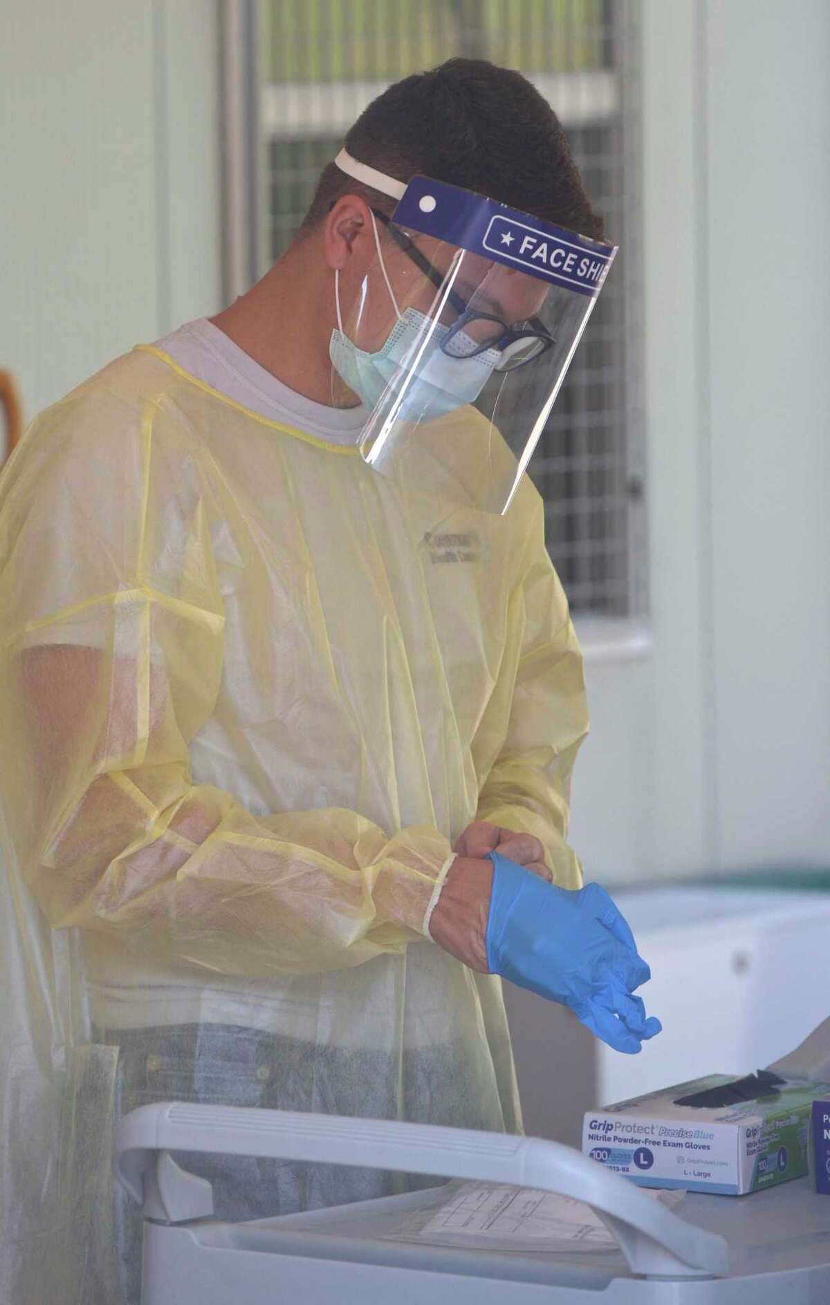 Peter Avila, a COVID testing associate, puts on glove to distribute a self administered test to a patient at the Community Health Center COVID-19 testing site on the Western Connecticut State University Westside Campus. Tuesday, June 29, 2021, in Danbury, Conn.