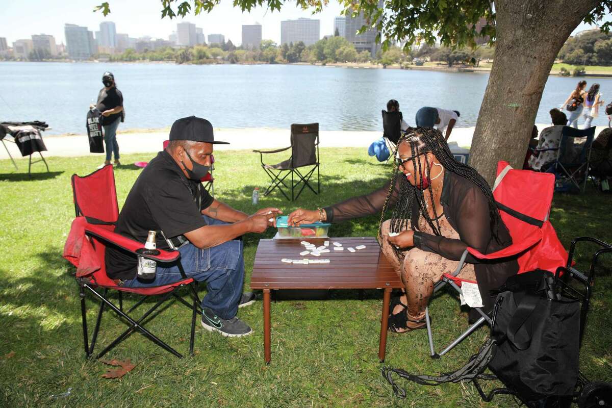 Michael Flemings, 67, of Stockton, plays dominoes with his daughter, Felita Flemings, 49, of San Francisco, at Lake Merritt in Oakland in 2020. Domino games are a familiar sight at many Black Bay Area family gatherings on the Fourth of July.