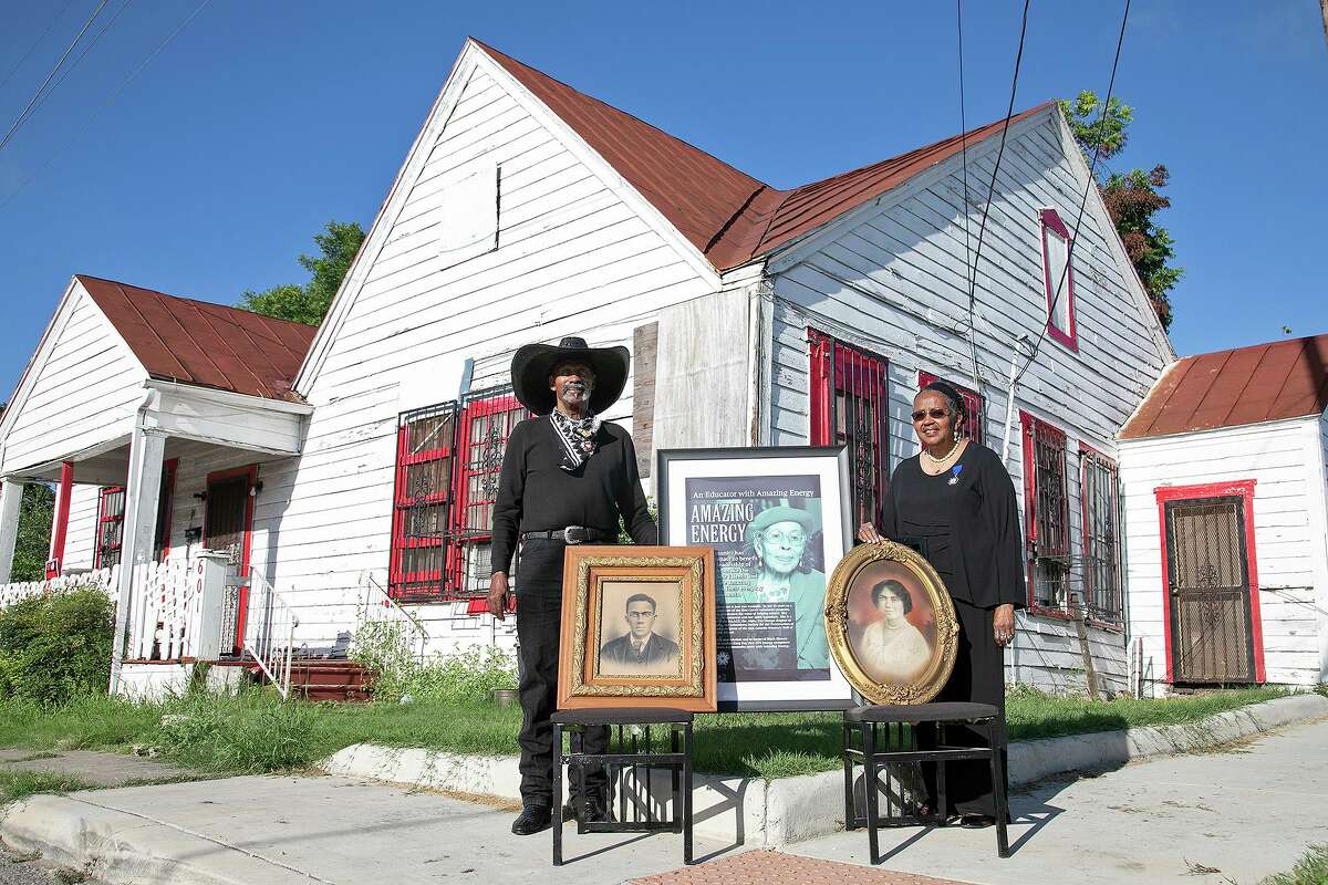 Ernest Stevenson Qadimasil II and his sister, Maria Stevenson Greene, stand with photographs of their mother, Henrietta Eugene Roberts Stevenson, center, who was born in the house behind them in 1915, and their grandparents, Lawyer Henry Porterfield Roberts, left, and Ira Aldridge Kilpatrick Roberts, outside the home where their grandparents lived with their mother in San Antonio on July 2, 2021.