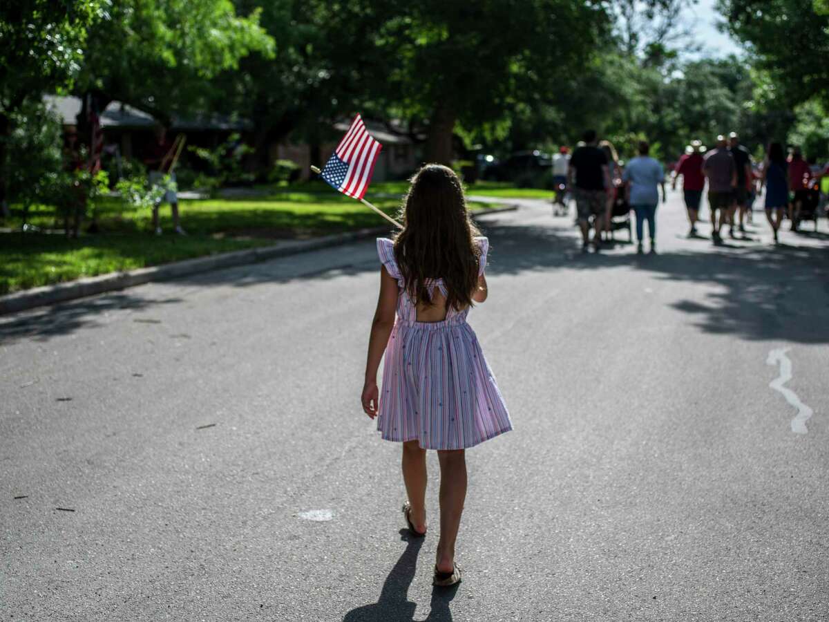 Community members wave flags and encourage neighbors to celebrate during the 25th annual Oak Park-Northwood Fourth of July Neighborhood Parade on Saturday. The neighborhood association organized the event.
