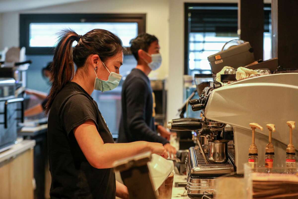 Jada Yee prepares a beverage at Henry’s House of Coffee in San Francisco. While the coffee house doesn’t require customers to wear masks, employees continue to do so due to confusing rollout of workplace safety measures statewide.