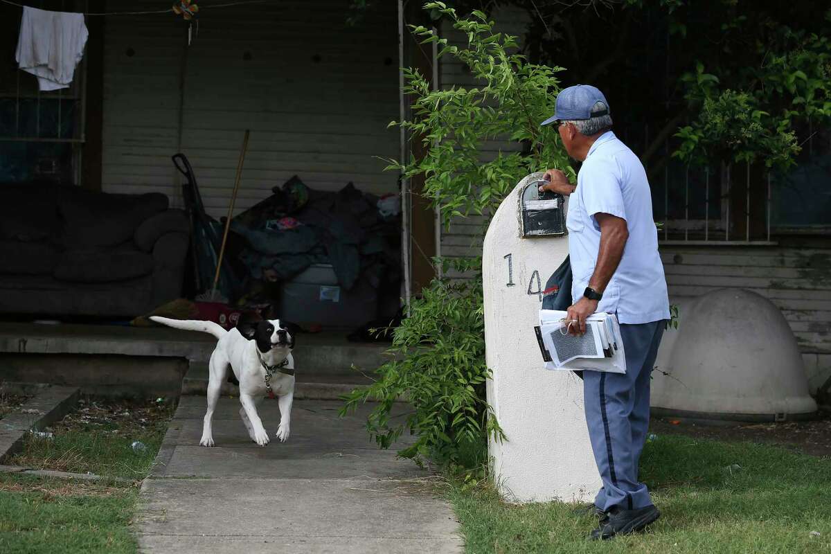 A tied-up dog greets U.S Postal Service letter carrier Joe Valadez, 59, while he makes his rounds on the East Side. “You never know what the dog is going to do,” Valadez says. 