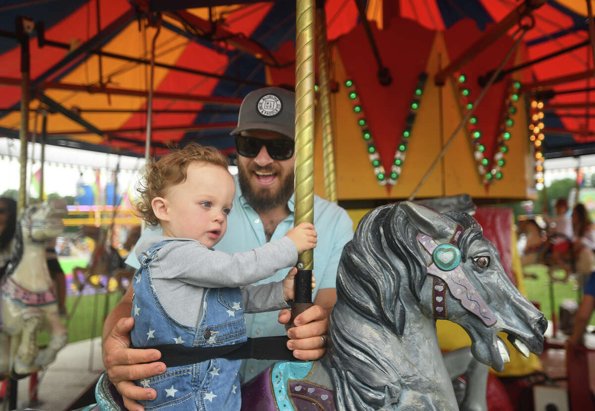 William Baruch, 1, of Fairfield, and his dad, Eli, take a ride on the carousel during Trumbull Day at Hillcrest Middle School in Trumbull, Conn. on Sunday, July 04, 2021.