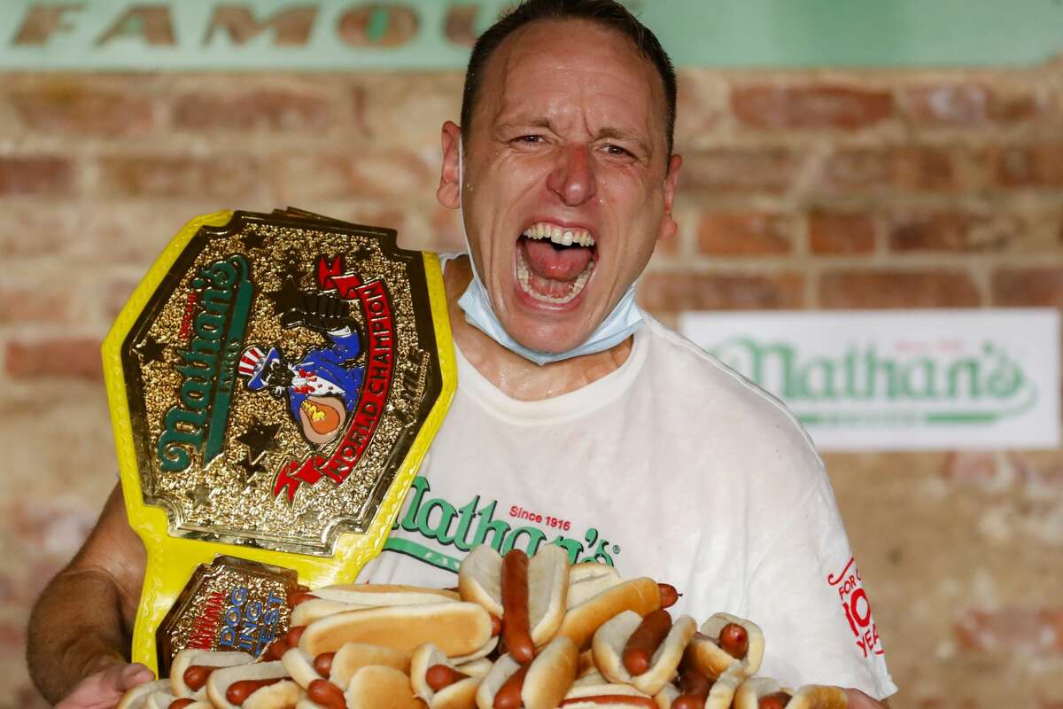 Competitive eater Joey Chestnut celebrates after setting a new world record with 75 hot dogs to win the men's division of the Nathan's Famous July Fourth hot dog eating contest, Saturday, July 4, 2020, in the Brooklyn borough of New York. (AP Photo/John Minchillo)