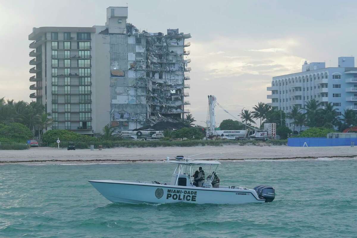 A Miami-Dade County Police boat patrols the ocean in front of the partially collapsed Champlain Towers South condo building, where demolition experts were preparing to bring down the precarious still-standing portion, Sunday, July 4, 2021, in Surfside, Fla. The decision to demolish the Surfside building came after concerns mounted that the damaged structure was at risk of falling, endangering the crews below and preventing them from operating in some areas.