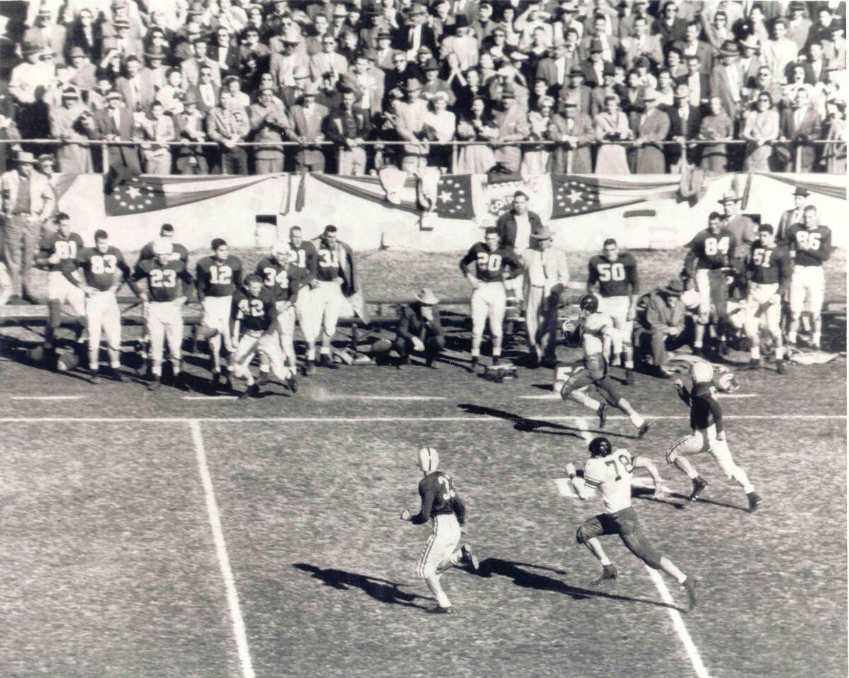 Dick Maegle of Rice runs with the ball down the sideline in the 1954 Cotton Bowl against Alabama. At left, Alabama's Tommy Lewis (42) is seen taking steps toward the field. courtesy of the Cotton Bowl,