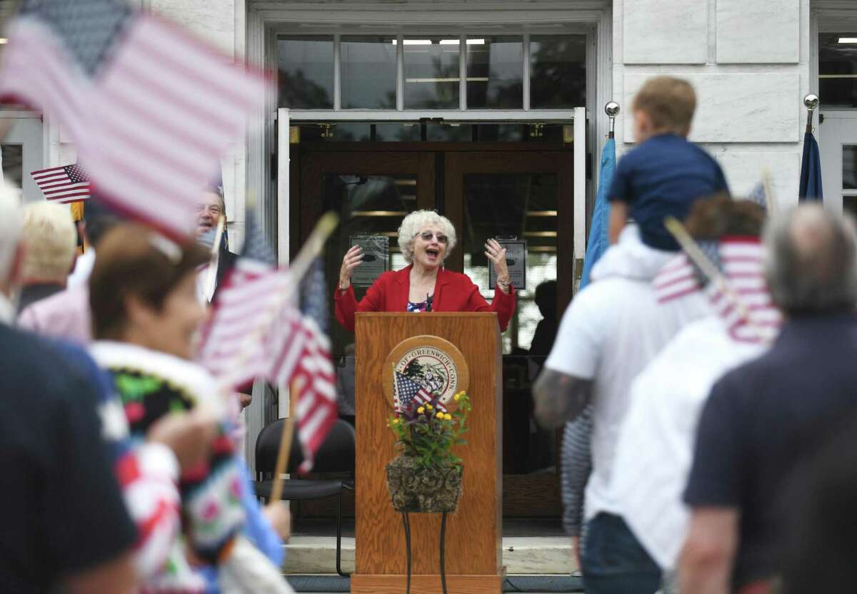 Stefanie Kies sings "God Bless America" as the crowd waves flags during the Fourth of July Celebration at Town Hall in Greenwich, Conn. Sunday, July 4, 2021. Presented by the Independence Day Association of Greenwich, the ceremony featured a flag raising, patriotic songs, reading of the Declaration of Independence, and honoring of Revolutionary War patriots.