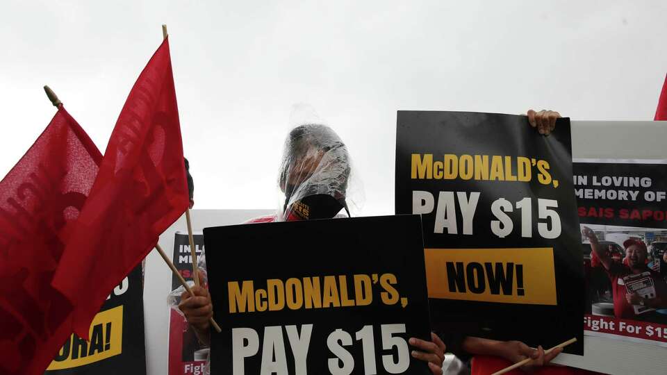 Marina Ramirez, center, takes part in a moment of silence for a man who passed away from COVID-19 related complications, during a protest at a McDonald's location Wednesday, May 19, 2021, at the intersection of Almeda Genoa Road and Highway 288 in Houston. The group was part of the Houston chapter of the Fight for $15 union, and they were protesting for higher wages. Ramirez said she works two jobs at two McDonald's locations, both part-time, to take care of her two boys. She described working roughly 100 hours each two-week period and still struggling to afford the family's needs. 'It's very hard for one person to do that,' she said through a translator.