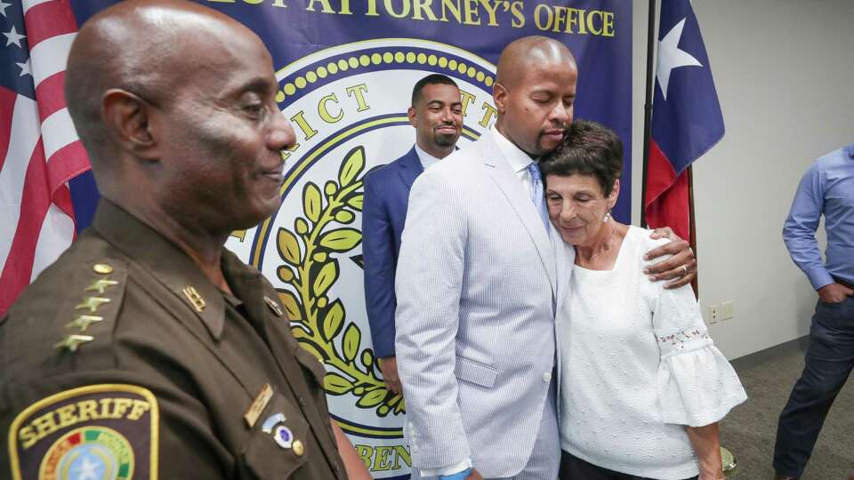 State Representative Ron Reynolds hugs Elaine Brooks, mother of Lisa Torry Smith as Fort Bend Sheriff Eric Fagan (left) and District Attorney Brian Middleton stand after a press conference to announce the passage of a bill creating criminal penalties for striking and killing a pedestrian in a crosswalk Tuesday, July 6, 2021, in Richmond.