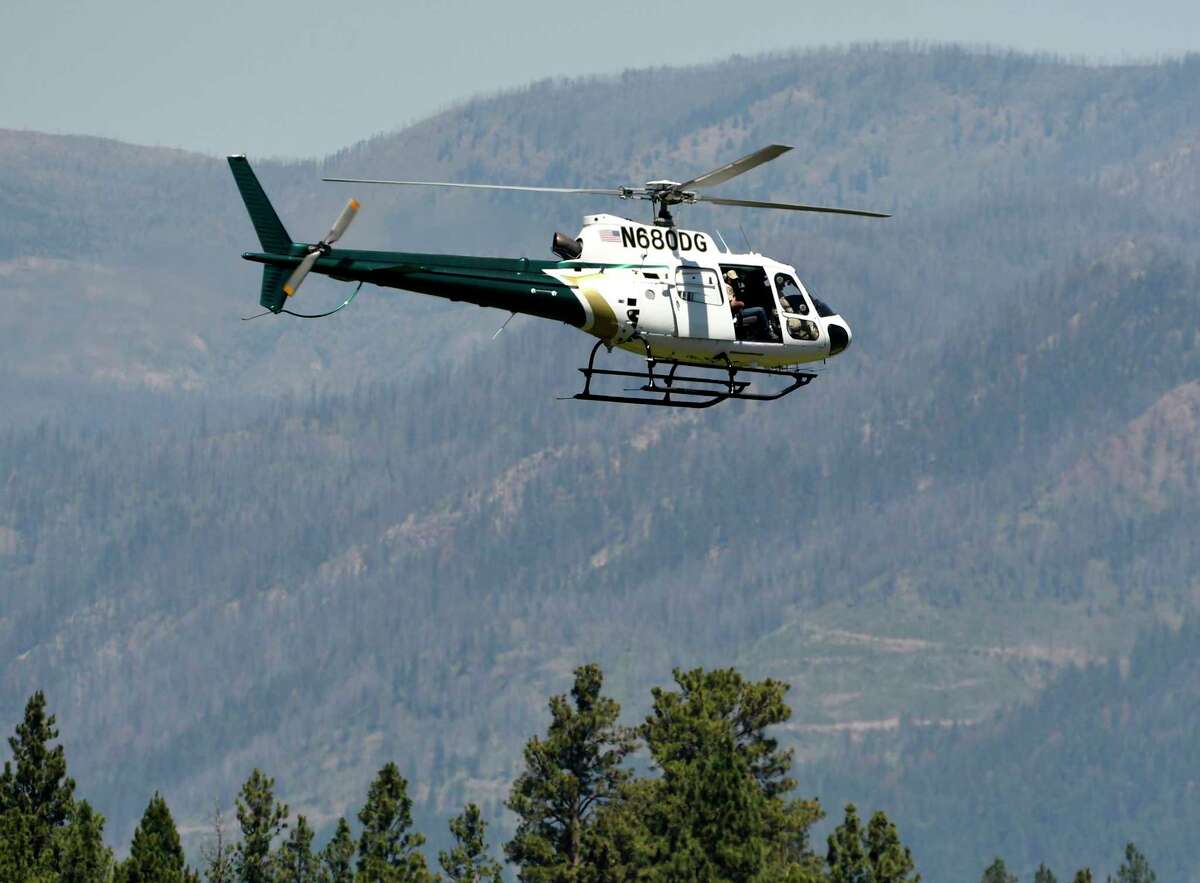 A helicopter from Montana Fish, Wildlife and Parks flies around the Ovando, Mont., area on Tuesday, July 6, 2201, in search of a bear that killed a camper early that morning. The search for the bear continued Wednesday. (Tom Bauer/The Missoulian via AP)