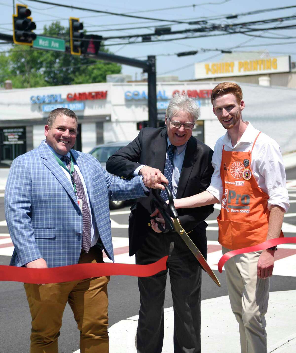 Stamford Transportation, Traffic & Parking Interim Bureau Chief Frank Petise, left, Stamford Mayor David Martin, center, and Home Depot Supervisor John Vincent cut the ribbon at the new and improved intersection of West Avenue and West Main Street in Stamford, Conn. Wednesday, July 7, 2021. The problematic intersection was recently renovated to add turning lanes from each direction to improve traffic flow.