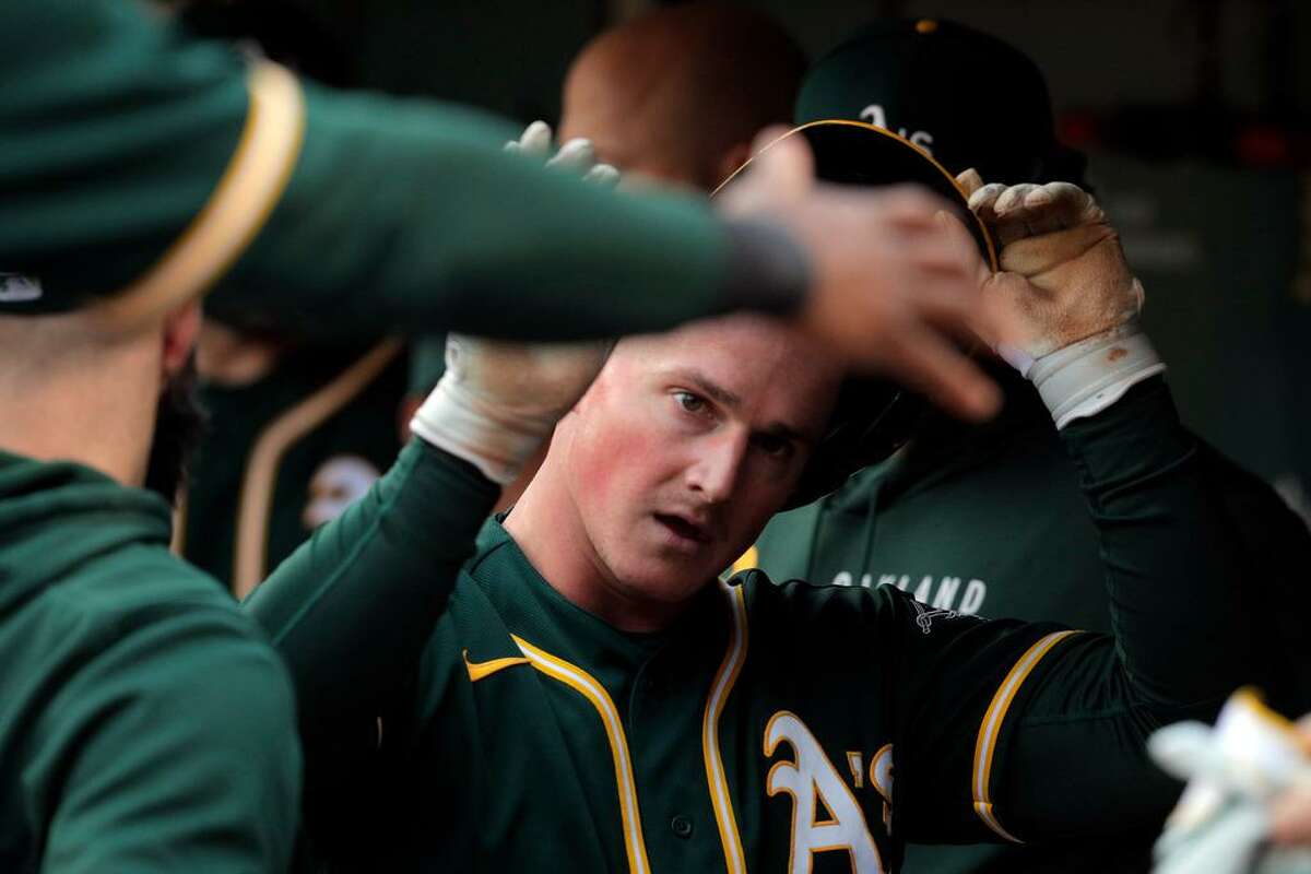 Matt Chapman (26) gets high fives from teammates iafter scoring in the second inning as the Oakland Athletics played the Texas Rangers at the Coliseum in Oakland, Calif., on Wednesday, June 30, 2021.