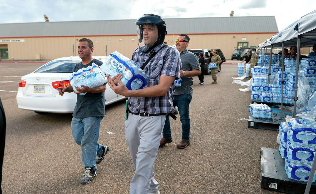 Laredo College employees Daniel Guerrero, Marco A. Mondragon and Sergio Martinez deliver cases of water to vehicles, Thursday, July 7, 2021, at Laredo College during a water distribution in response to a city wide boil water notice.