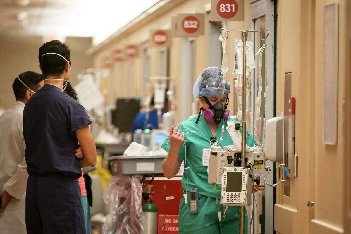Memorial Hermann Hospital RN Courtney Aiken works on IV lines outside of a patient's room inside a 38-bed ICU treating mostly COVID patients, Tuesday, Jan. 5, 2021, in Houston's Texas Medical Center.