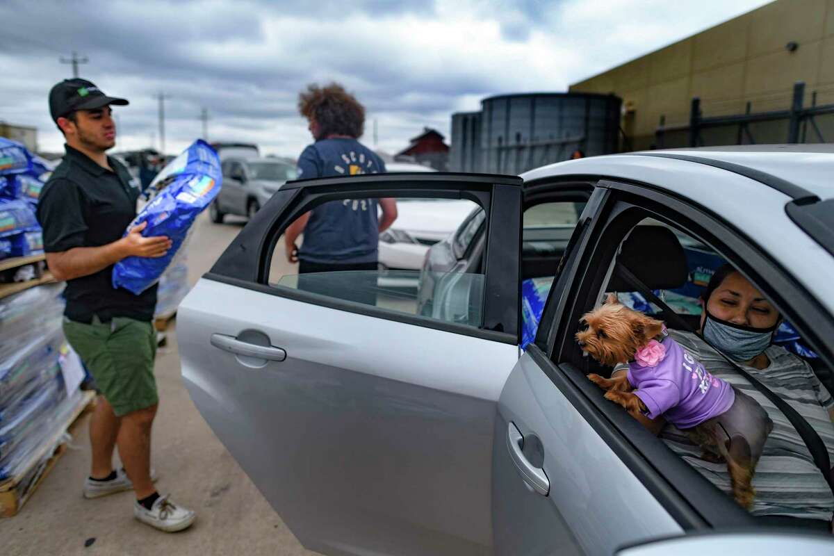 Trudy the dog barks as San Antonio Food Bank volunteers load bags of pet food donated by PetSmart Charities on Thursday, July 8, 2021. With Trudy is Mari Casarez.