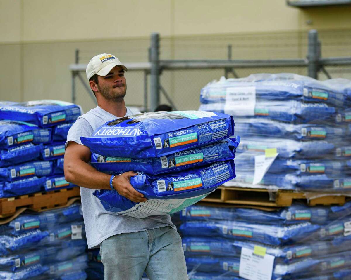 Cameron Reeves, a volunteer from Highland Park United Methodist Church in Dallas, carries some of the 15 truckloads of pet food donated by PetSmart Charities for distribution by the San Antonio Food Bank on Thursday, July 8, 2021.