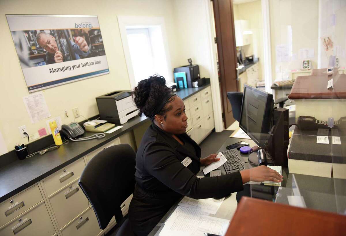 Bank teller Taishara Blanco assists a customer at First County Bank in Stamford, Conn. Thursday, July 8, 2021.