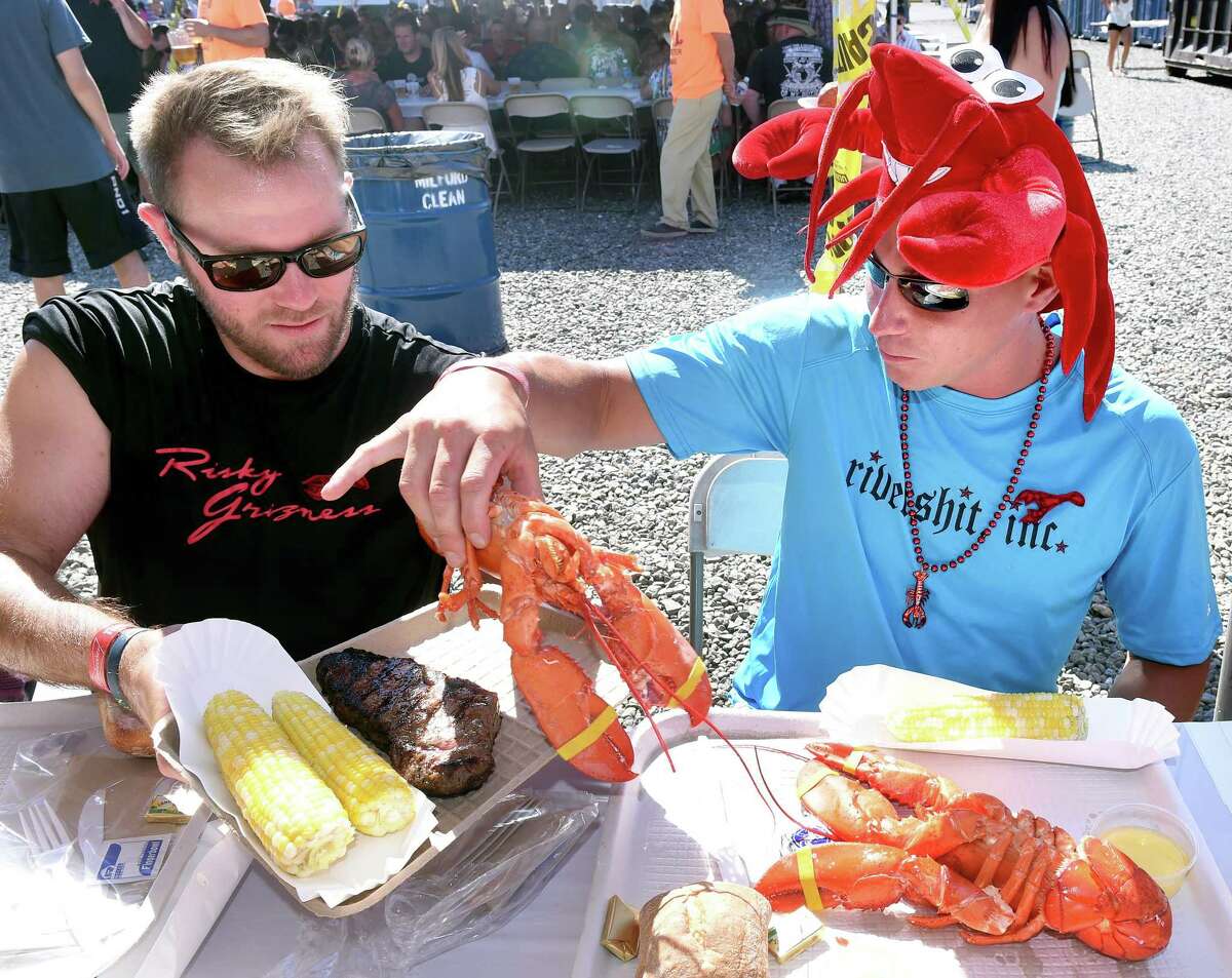 Travis Bokina (left) trades half of a steak for a lobster with Daniel Krotki at the Milford Rotary's 40th Annual Lobster Bake at Milford Boat Works on 7/23/2016. Both are from Milford. The 2021 fundraiser has been canceled, marking the second year COVID-19 has impacted the annual event.