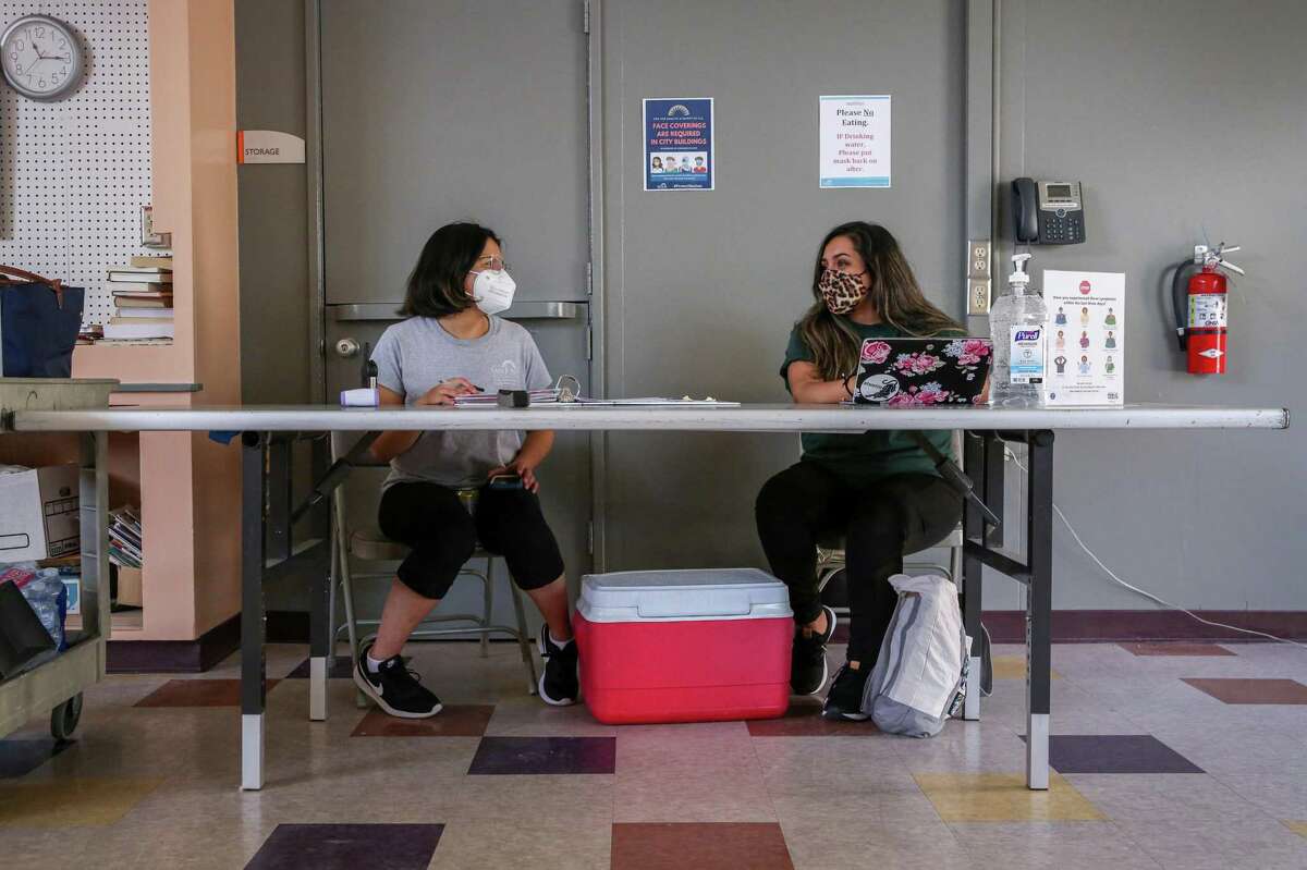 From left, recreation leaders Mariah Tapia and Nicole Rodriguez Calderon chat while at a screening station in a cooling center at Camden Community Center in San Jose, Calif. on Wednesday, June 16, 2021. The cooling station was open again on Saturday, July 10, 2021, amid another scorching heat wave.