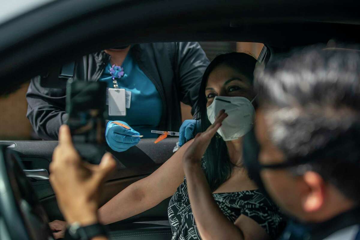 Karla De Leon waves for a picture by Pablo Melgar as she receives her COVID-19 vaccine Saturday at the Spring Branch Community Health Center. De Leon and Melgar traveled from Guatemala to get the one-dose Johnson & Johnson shot.