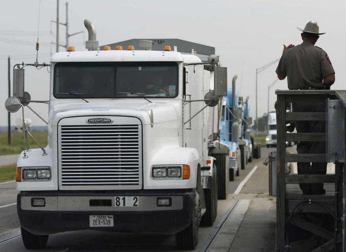 In this file photo, a Texas Department of Public Safety trooper motions a trucker off the scales at an Interstate 35 weigh station in San Marcos. More than a half-million overweight trucks are allowed onto the nation’s roads and bridges.