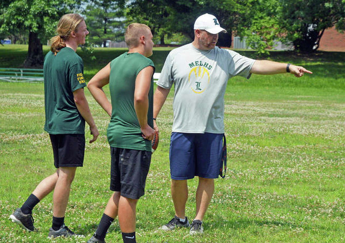Metro-East Lutheran football coach Mike Koch, right, talks to seniors Kaiden Downs, left, and Peyton Wren during a summer practice session last week.