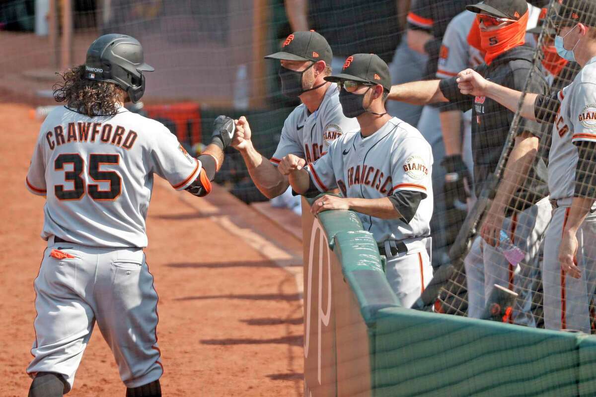 San Francisco Giants' Brandon Crawford is greeted by manager Gabe Kapler after Crawford's 6th inning grand slam against Oakland Athletics in MLB game at Oakland Coliseum in Oakland, Calif., on Sunday, September 20, 2020.
