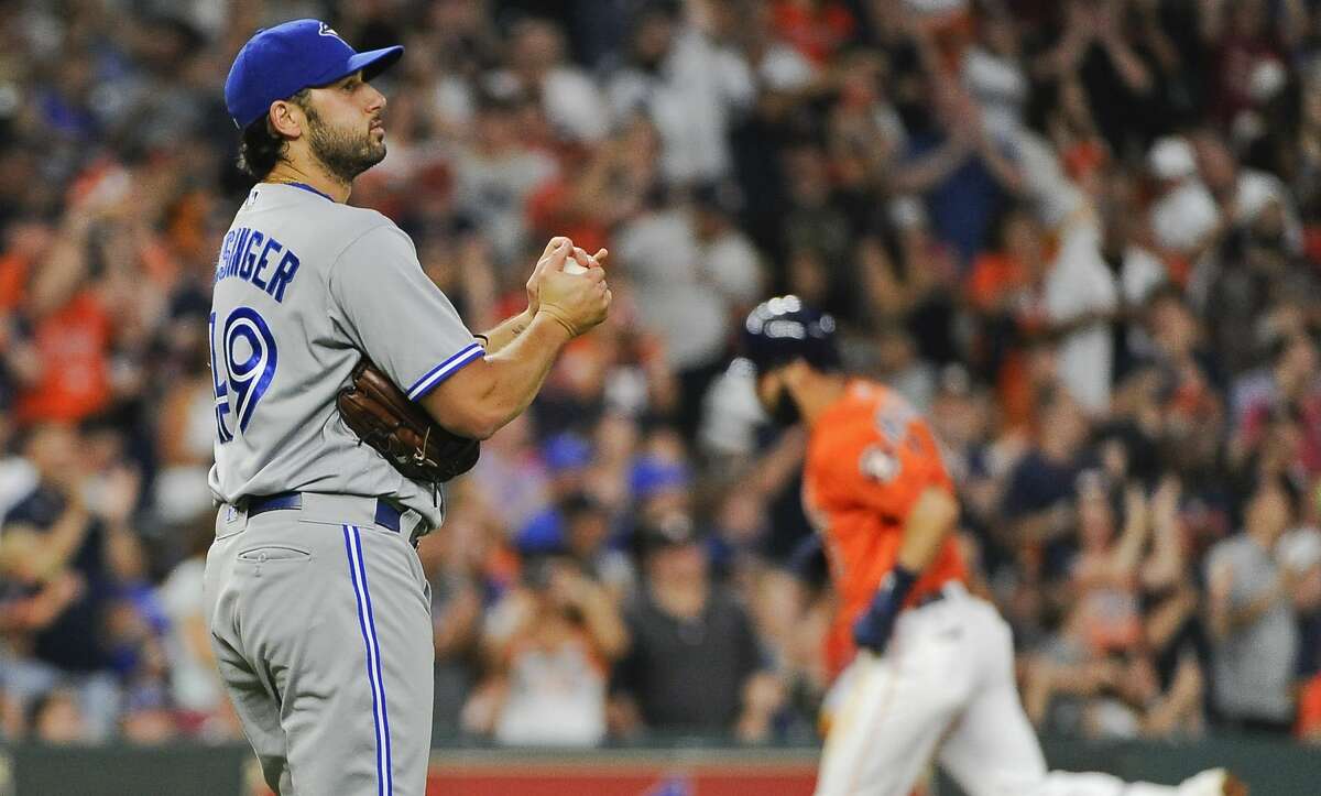 In this Aug. 4, 2017 file photo, Toronto Blue Jays relief pitcher Mike Bolsinger, left, walks off the mound as Houston Astros' Marwin Gonzalez rounds the bases after hitting a three-run home run during the fourth inning of a baseball game in Houston. Bolsinger sued the Astros, claiming their sign-stealing scheme contributed to a poor relief appearance that essentially ended his big league career.